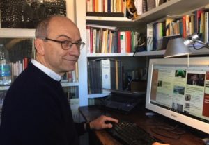 Il giornalista ambientale Antonio Cianciullo seduto alla sua scrivania, con il computer davanti e la libreria sullo sfondo