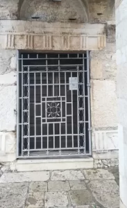 Un pezzo di fregio dorico riusato come stipite per il portone.